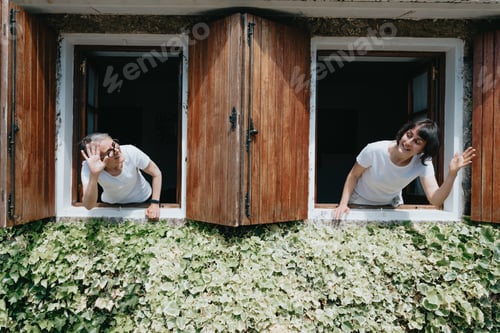 Preview: Old woman and his daughter having fun at the windows during a super sunny day, smiling