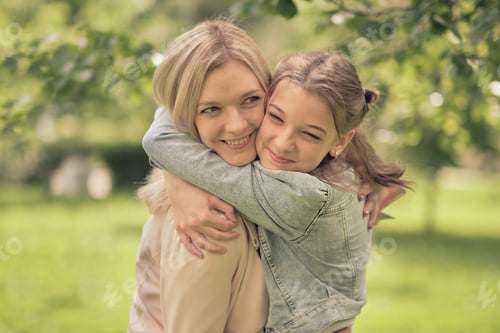 Preview: happy mother with her daughter hugging a teenager in the summer.