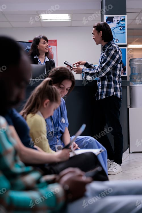 Preview: Asian patient at hospital front desk paying at pos using credit card for medical services