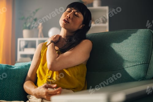 Preview: Asian lady relaxing in teal armchair slightly adjusting her hair