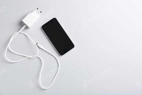 Preview: USB power adapter with charge cable and smartphone on white background, flat lay. Space for text