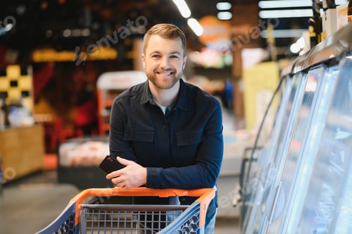 Preview: Handsome man buying some healthy food and drink in modern supermarket or grocery store