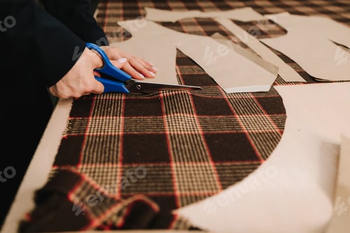 Preview: Designer slices fabric along markings with scissors, preparing garments and apparel.