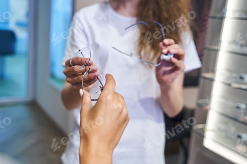 Preview: Young woman choosing eyeglasses in optical store