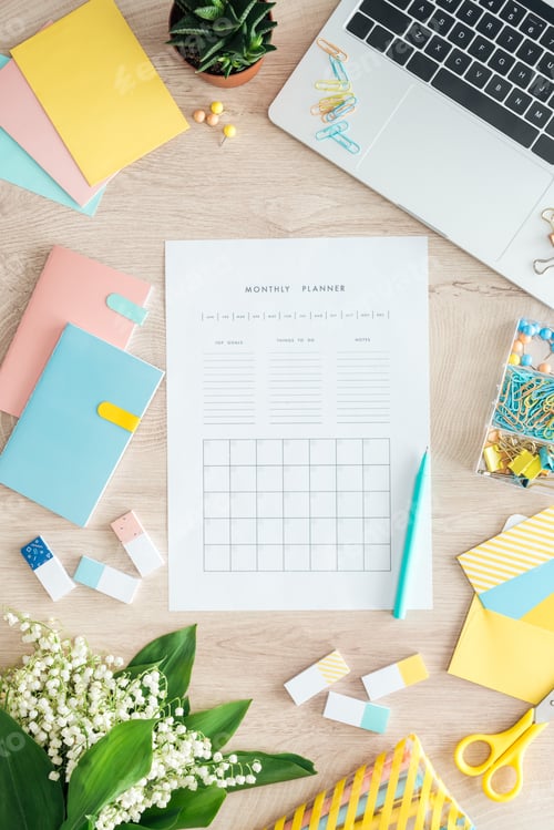 Preview: top view of monthly planner, stationery, flowers and laptop on wooden table