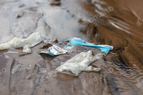 Preview: Waste during COVID-19. Single-use coronavirus face masks and gloves discarded in the ocean, closeup