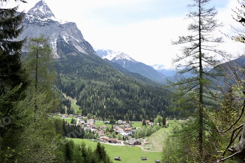 Preview: A beautiful landscape with a lot of buildings surrounded by trees and high rocky mountains