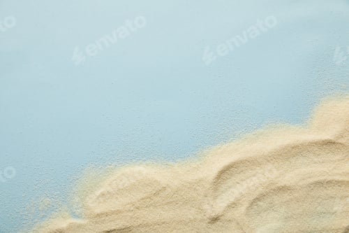Preview: top view of textured wavy golden sand on blue background with copy space