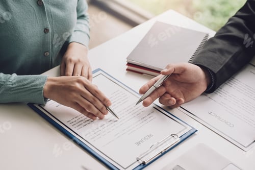 Preview: Image of a woman hand holding a pen reading a resume with contract documents at the office.