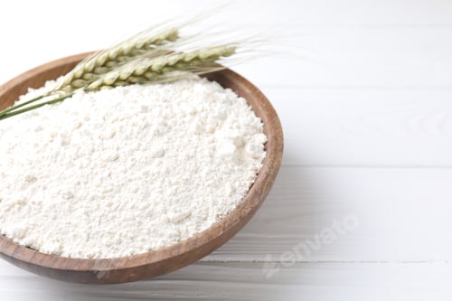 Preview: Flour and green wheat spikes in bowl on white wooden table, closeup. Space for text