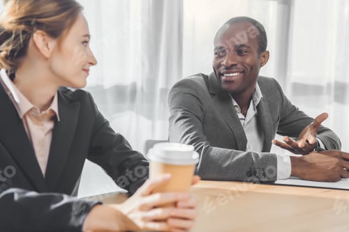 Preview: african man smiling to woman with coffe in hands at office space