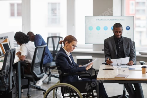 Preview: High angle portrait of businesswoman using wheelchair at business meeting in office and talking on