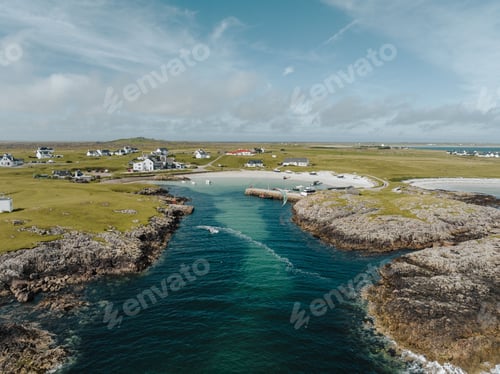 Preview: Aerial view of a sandy beach along Tiree island in Scotland with houses and a turquoise sea lagoo