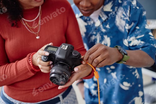 Preview: Young Adult Black Woman and Black Man Reviewing Photos on Digital Camera Together