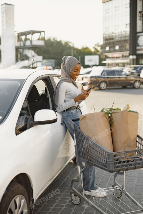 Preview: African muslim woman chraging car and use phone