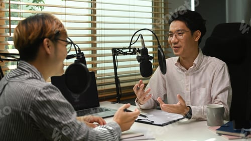 Preview: Image of radio host using microphone and laptop to recording podcast in home studio.