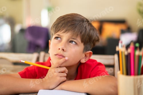 Preview: Young boy thinking while doing homework at home