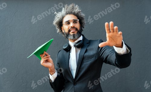 Preview: young entrepreneur throwing a green paper aircraft in the air.