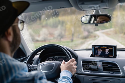 Preview: Man driving car while being on a day road trip.