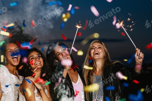 Preview: Four happy girls celebrating at night under colorful confetti holding sparkles and laughing