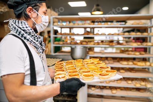 Preview: The baker is holding a tray of rice cake fresh leaving it on a tray cart to be sold at the bakery