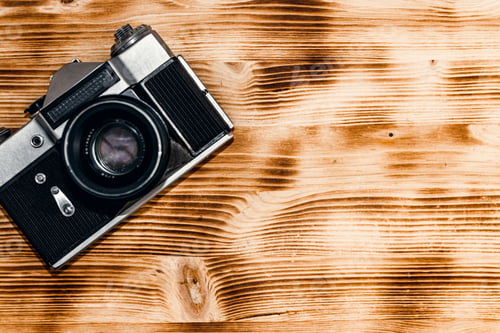 Preview: vintage old camera on a light brown wooden background. space for text