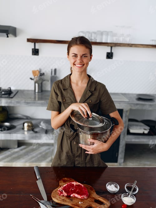 Preview: A woman in a stylish kitchen prepares food and holds a pot for cooking dinner in her hands and