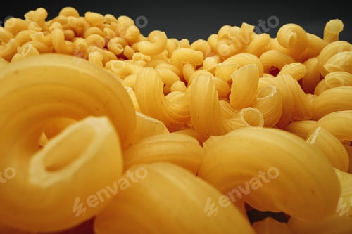 Preview: Uncooked pasta swirls on dark background macro