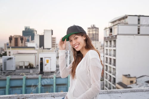 Preview: Young woman standing on a rooftop terrace, smiling