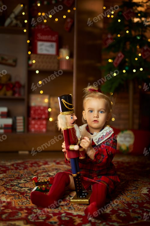Preview: Child with Christmas present. cute little girl in a red checkered dress