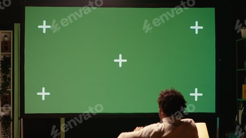 Preview: Man sitting on couch at home, relaxing by playing videogames on isolated screen ultrawide smart TV