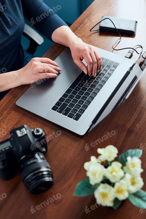 Preview: Female photographer working on photos on laptop and camera. Woman editing retouching browsing photos