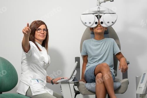 Preview: Asian boy with a phoropter at an optometrist consultation