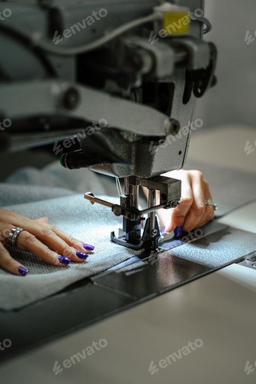 Preview: Vertical shot of female hands using a sewing machine