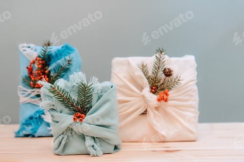 Preview: Zero waste gifts wrapped in fabric with spruce branch and berries on wooden background.