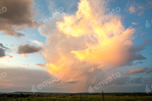 Preview: Dramatic yellow sunset over rural area with stormy puffy clouds lit by orange setting sun