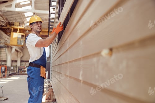 Preview: Cheerful worker building module house at construction site