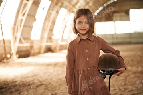 Preview: Little girl in jockey clothes is standing indoors