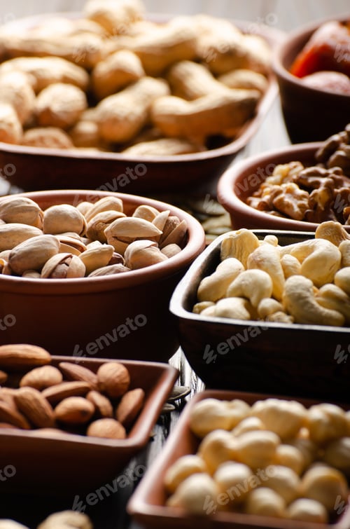 Preview: Assorted nuts and seeds in clay bowls on wooden kitchen table