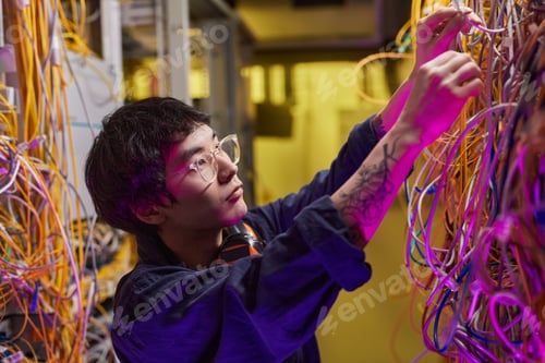 Preview: Young Technician Connecting Cables in Server Room