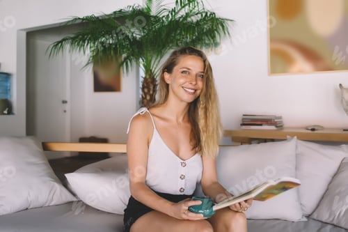 Preview: Cheerful woman having coffee break with book