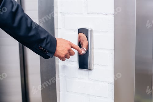 Preview: cropped shot of man in suit pressing elevator button