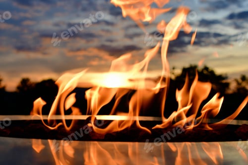 Preview: A summer sky sunset as seen through the flames of a fire table, firepit, bonfire, campfire.