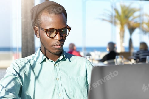 Preview: Serious concentrated dark-skinned fashionable student having frustrated look while working on his di