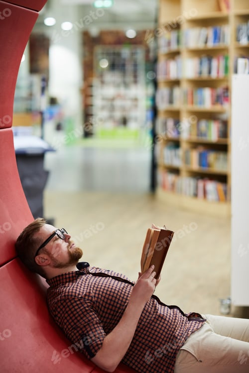 Preview: Bearded man reading book in library