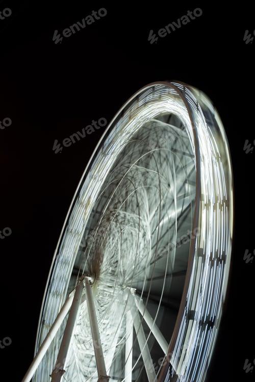 Preview: selective focus of blurred observation wheel at night on black background
