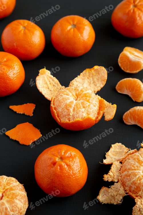 Preview: Raw Organic Mandarin Oranges on a black surface, side view.