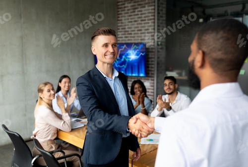 Preview: We're Hiring. Male HR Manager Handshaking With African American Employee In Office