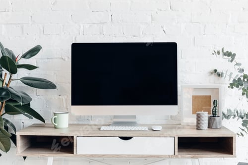 Preview: blank copmuter screen on modern workplace surrounded with flower pots, mockup concept