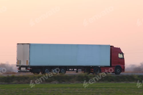 Preview: Semi-truck with cargo trailer driving on highway hauling goods in evening.